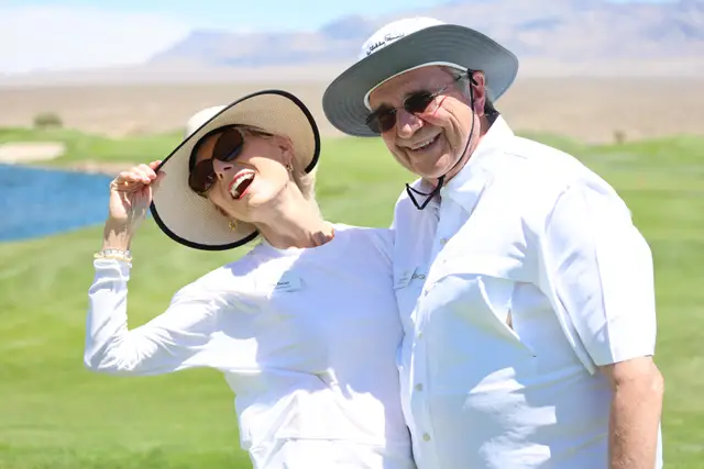 Two guests laughing together on the course with the lake behind