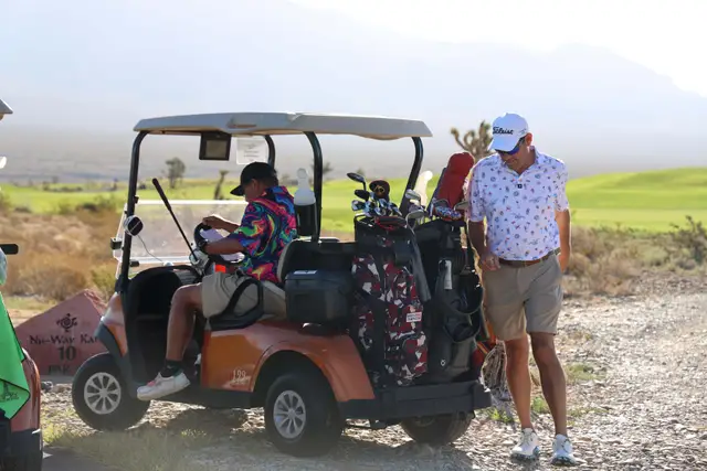 Two golfers with an orange cart at the hole 10 tee marker in the desert