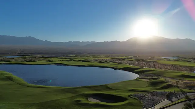 Aerial view at sunrise over a lake and green framed by bunkers and desert mountains